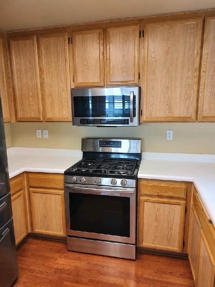 Kitchen with light wood cabinets, stainless steel appliances, and white countertops.