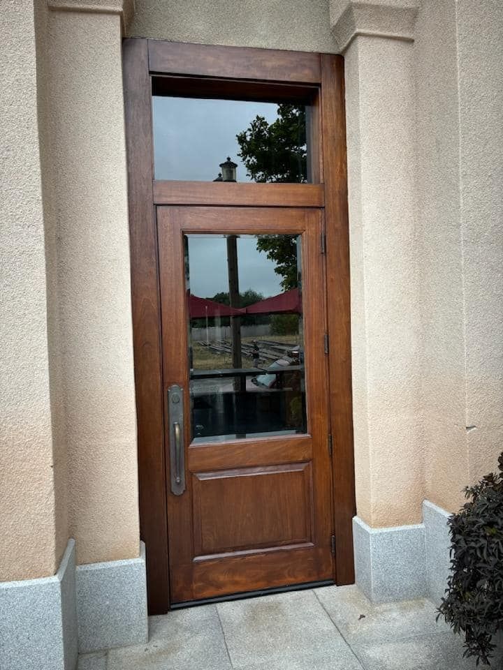 Wooden door with glass panels, set in beige stone doorway.