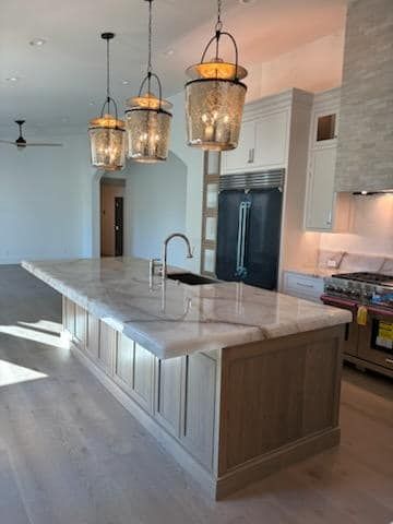 Open-concept kitchen with a marble-topped island, pendant lights, and stainless steel appliances.