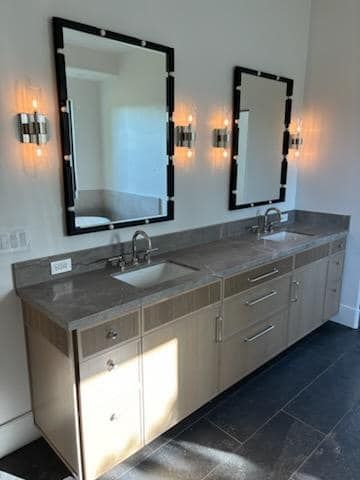 Bathroom with double sinks, large mirrors, light fixtures, and a light-colored countertop and cabinets.