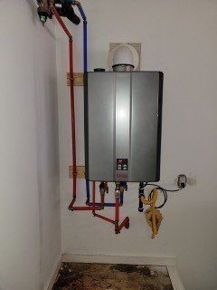 Wall-mounted gas boiler with exposed red and blue pipes in a utility room