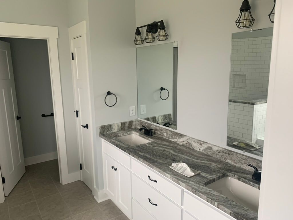 Bathroom with a white vanity, gray granite countertop, and large mirror.
