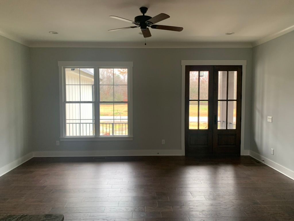 Room interior with dark wood floors, gray walls, white trim, a window, and French doors.