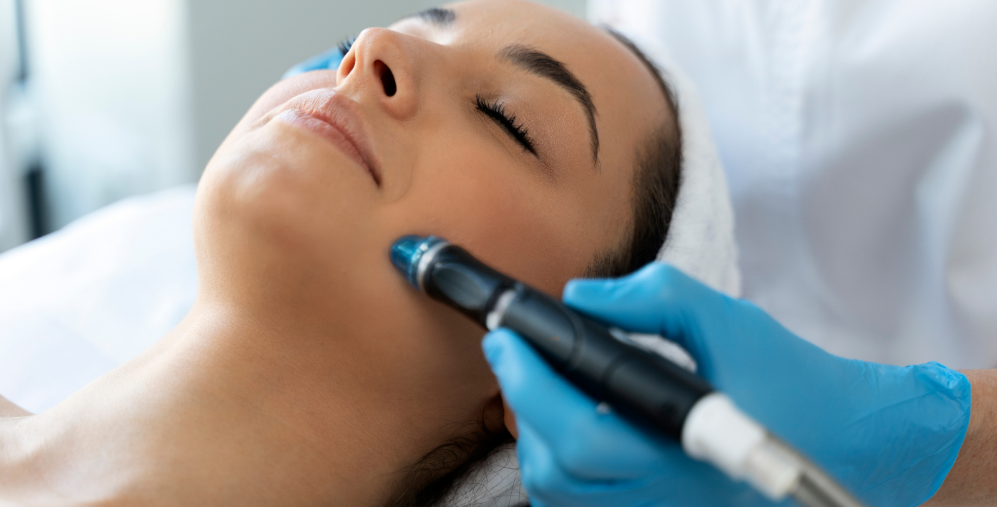Woman receiving a facial treatment with a handheld device on her face, in a spa setting.