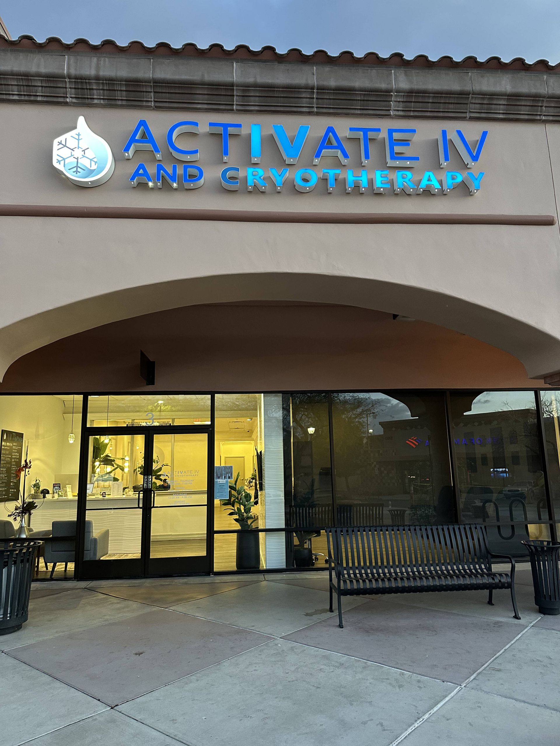 "Exterior of a business, Activate IV and Cryotherapy, with blue signage. Entryway with bench, and glass windows. "