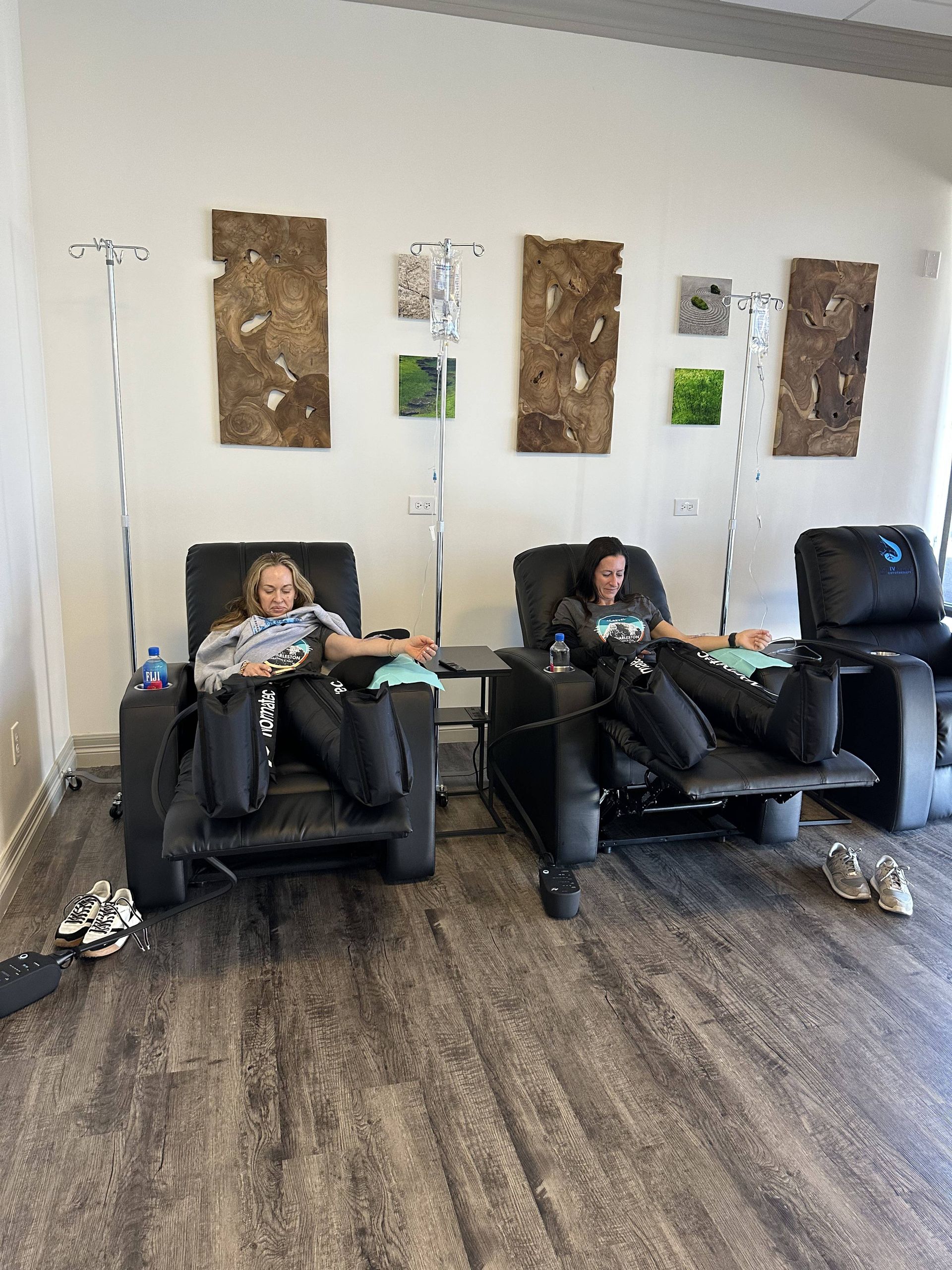 Two people reclining in chairs, receiving IV drips in a spa-like setting.