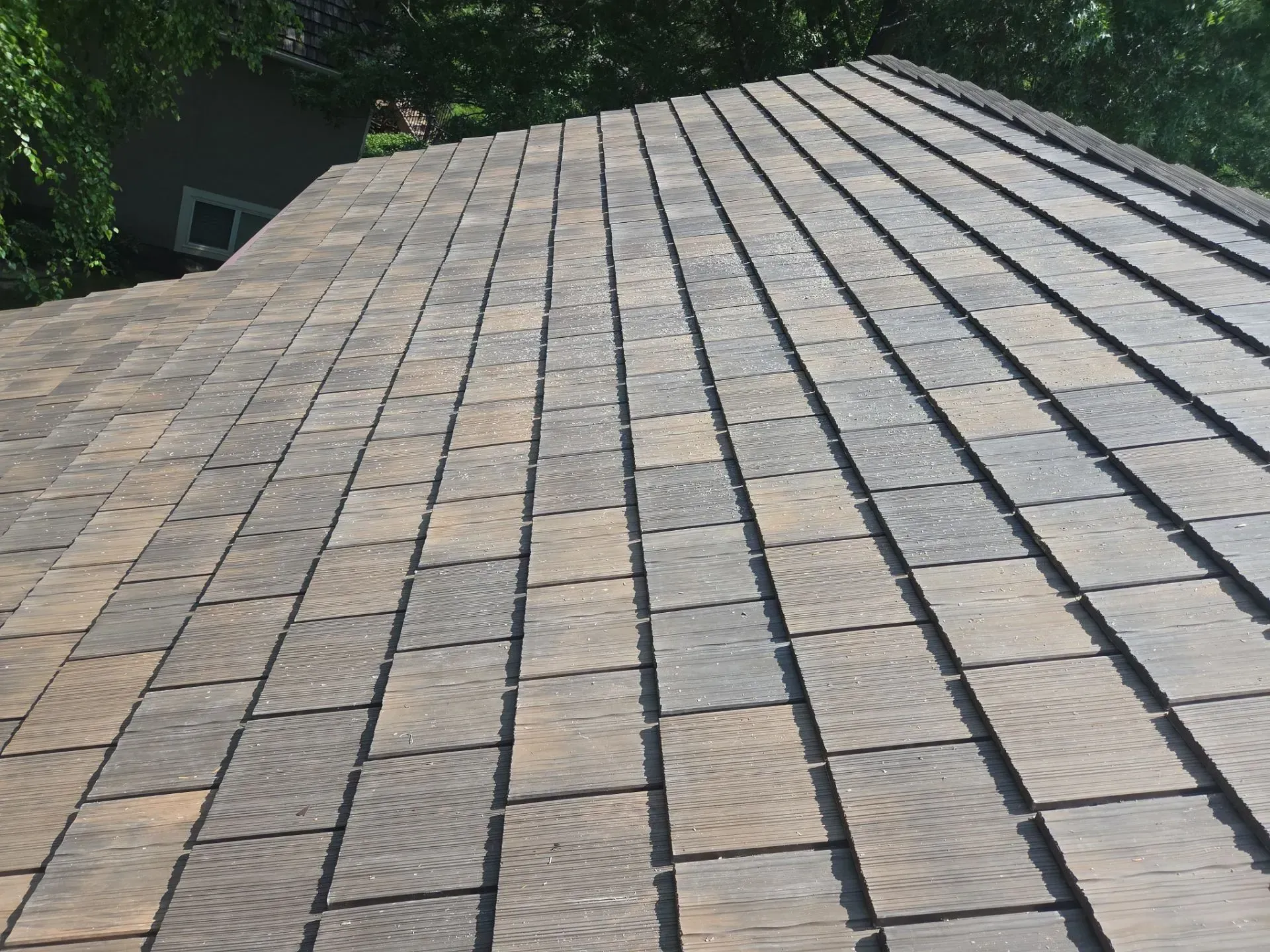Close-up of a multi-colored shingle roof, angled view under bright sunlight.