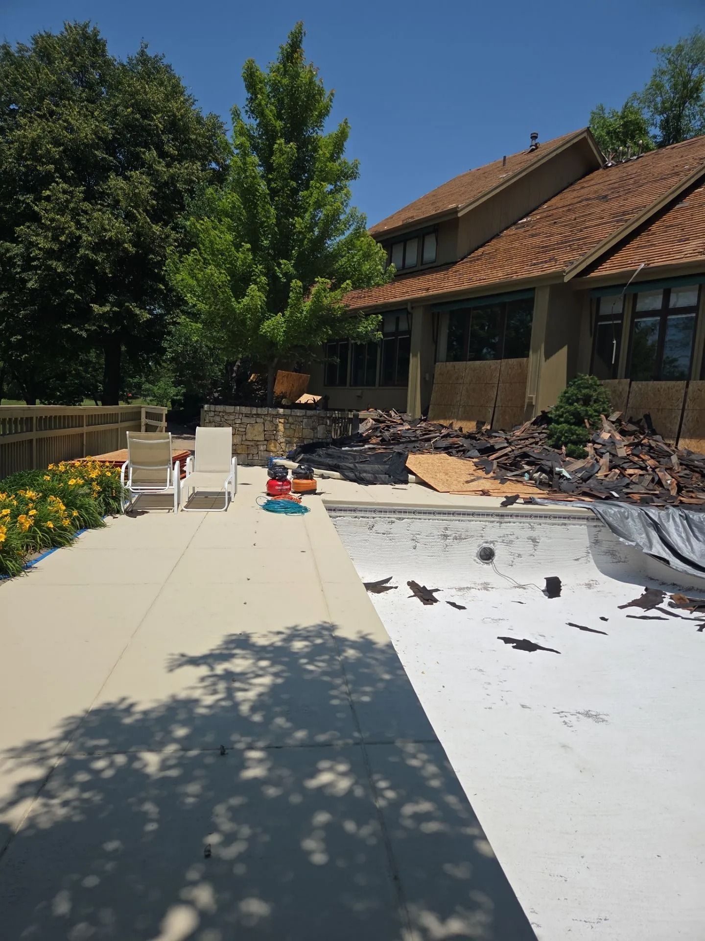 Pool and patio area under construction, with a house in the background.