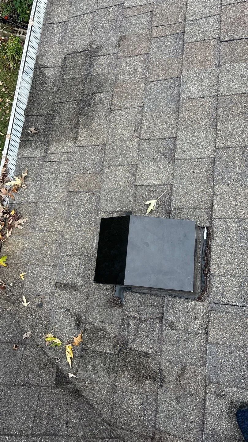 Damaged asphalt shingles on a roof with two replacement tiles.