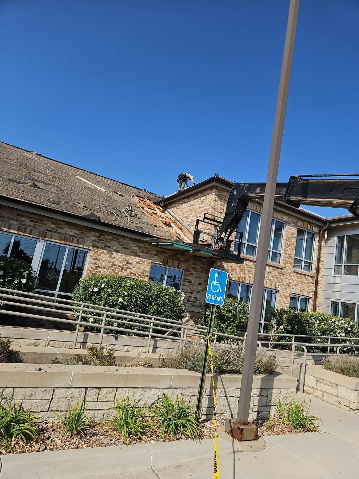 A building with damaged roof and wheelchair accessible sign. Sunny day with clear blue sky.