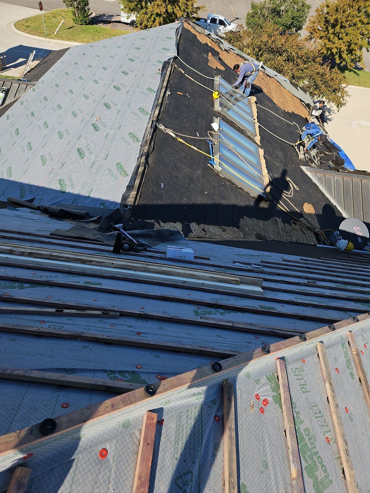 Roofers working on a building; some on the roof, others below. Sky lights present.