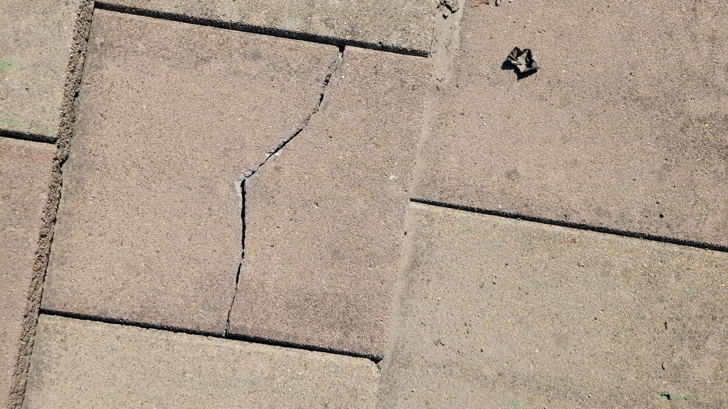 Cracked concrete patio tile; the crack curves across the center tile.