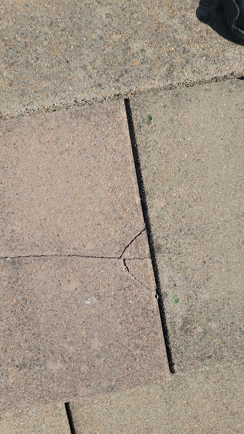 Concrete sidewalk with a long crack and small displacement.