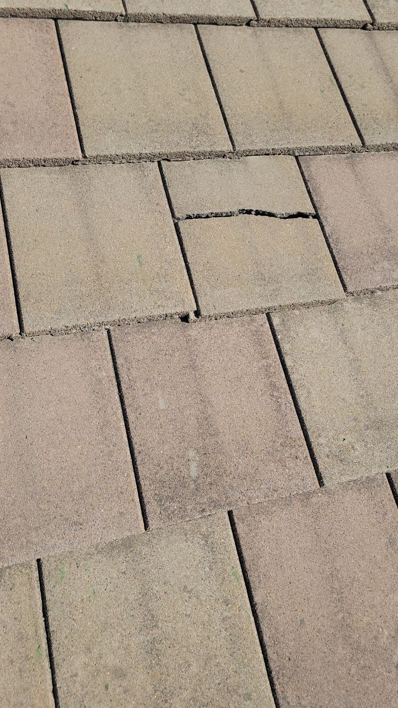 Close-up of weathered roof shingles, one cracked.