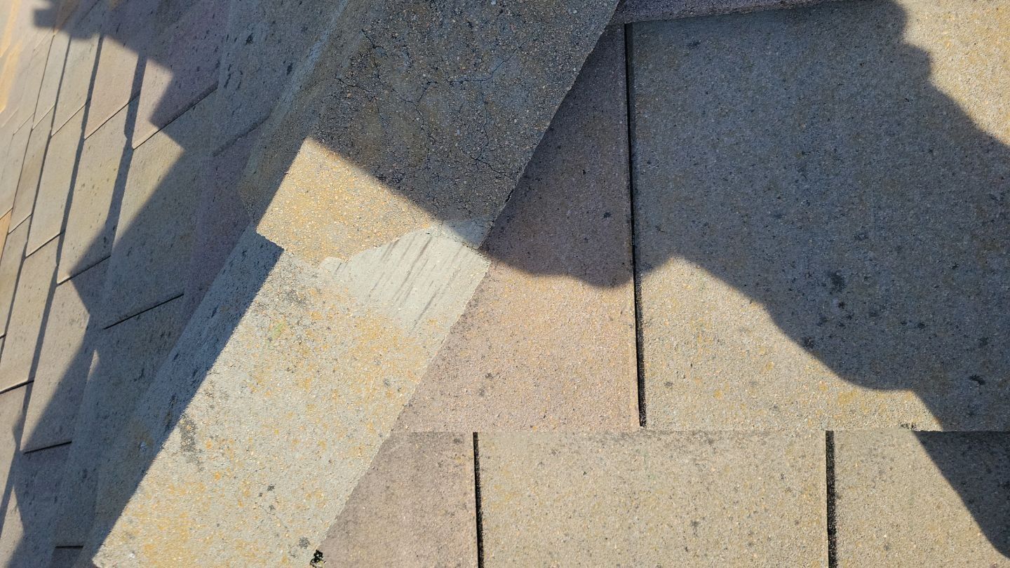 Close-up of asphalt shingle roof with shadows cast by sunlight.