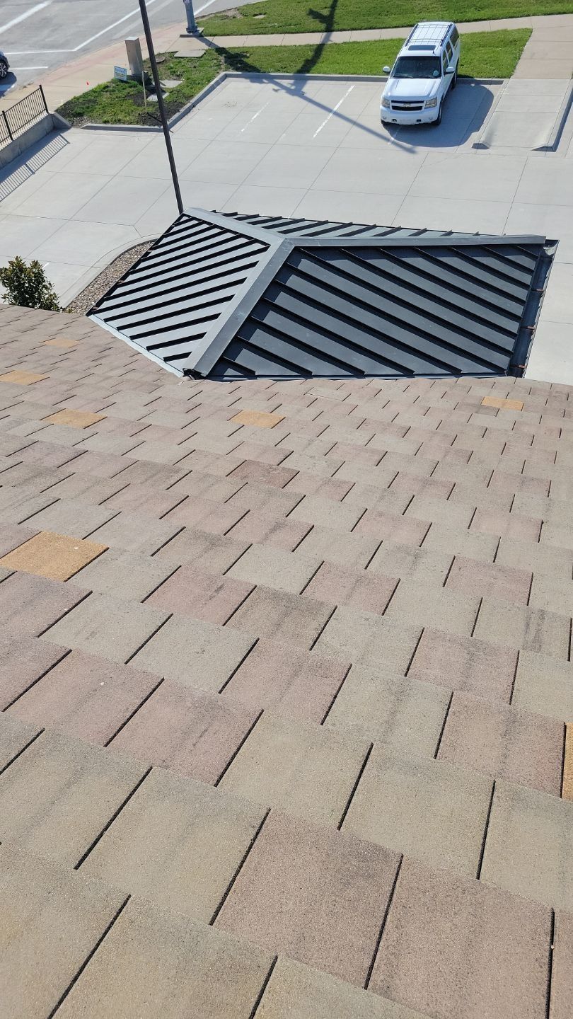 Brown shingle roof with a metal roof extension, viewed from above, on a sunny day.