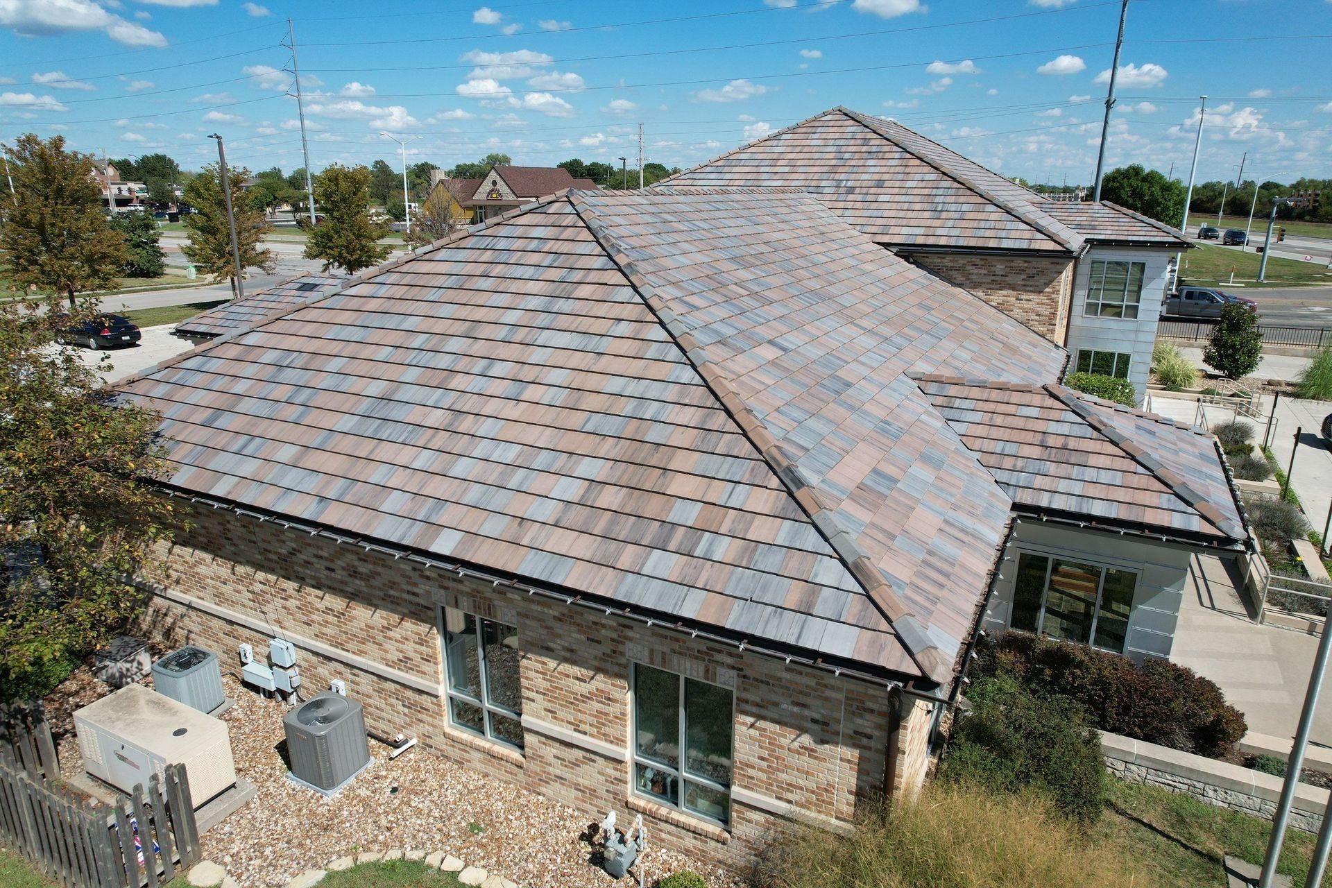 Brick home with multi-colored tile roof on a sunny day.