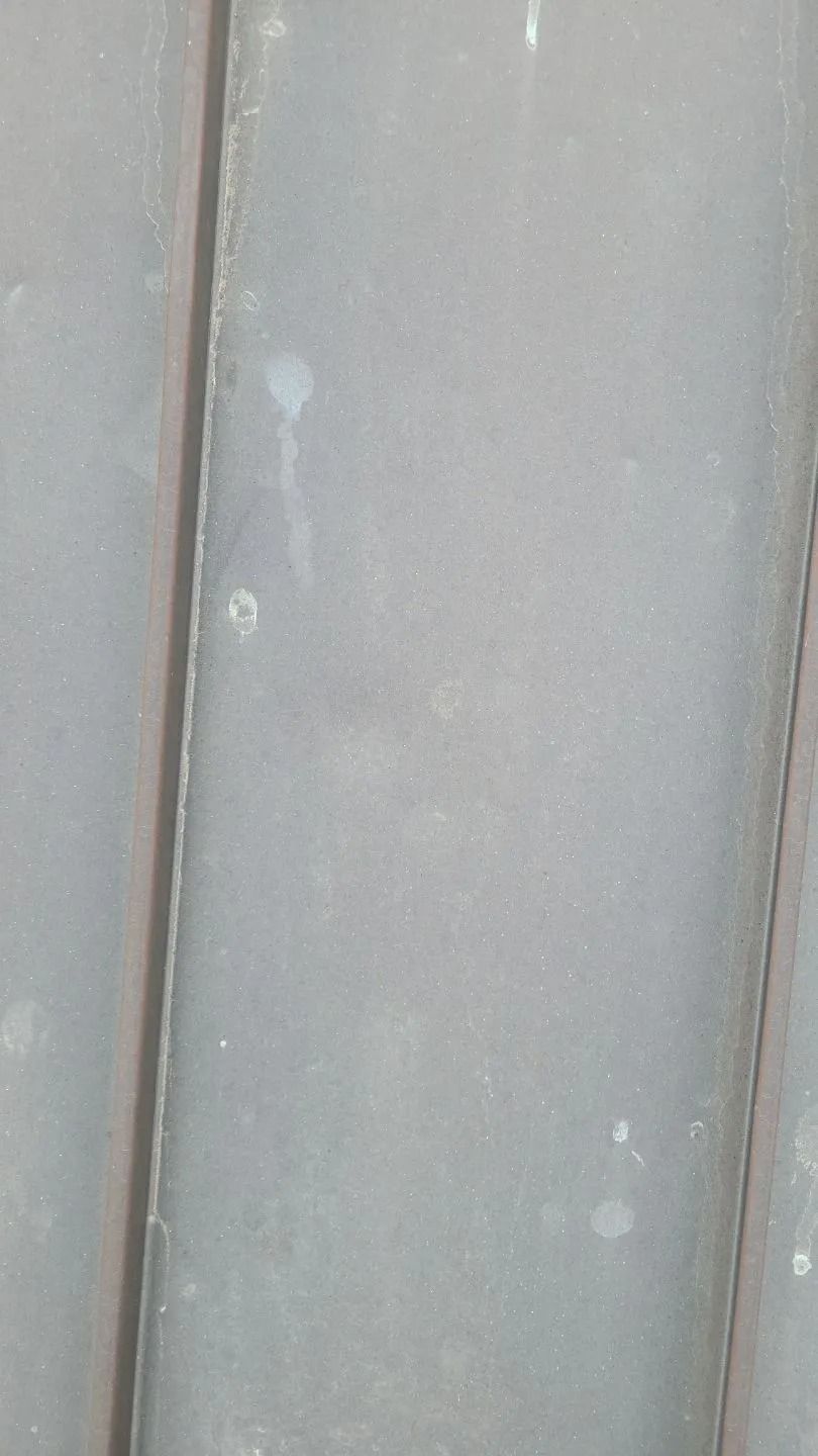 Gray metal surface with vertical lines, subtle imperfections.