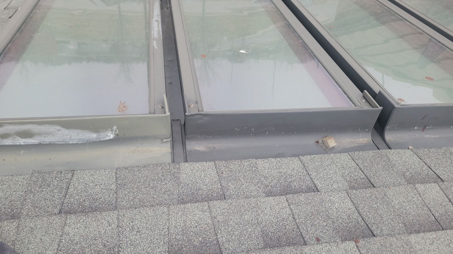 Skylights on a shingled roof, showing metal flashing and glass panels.