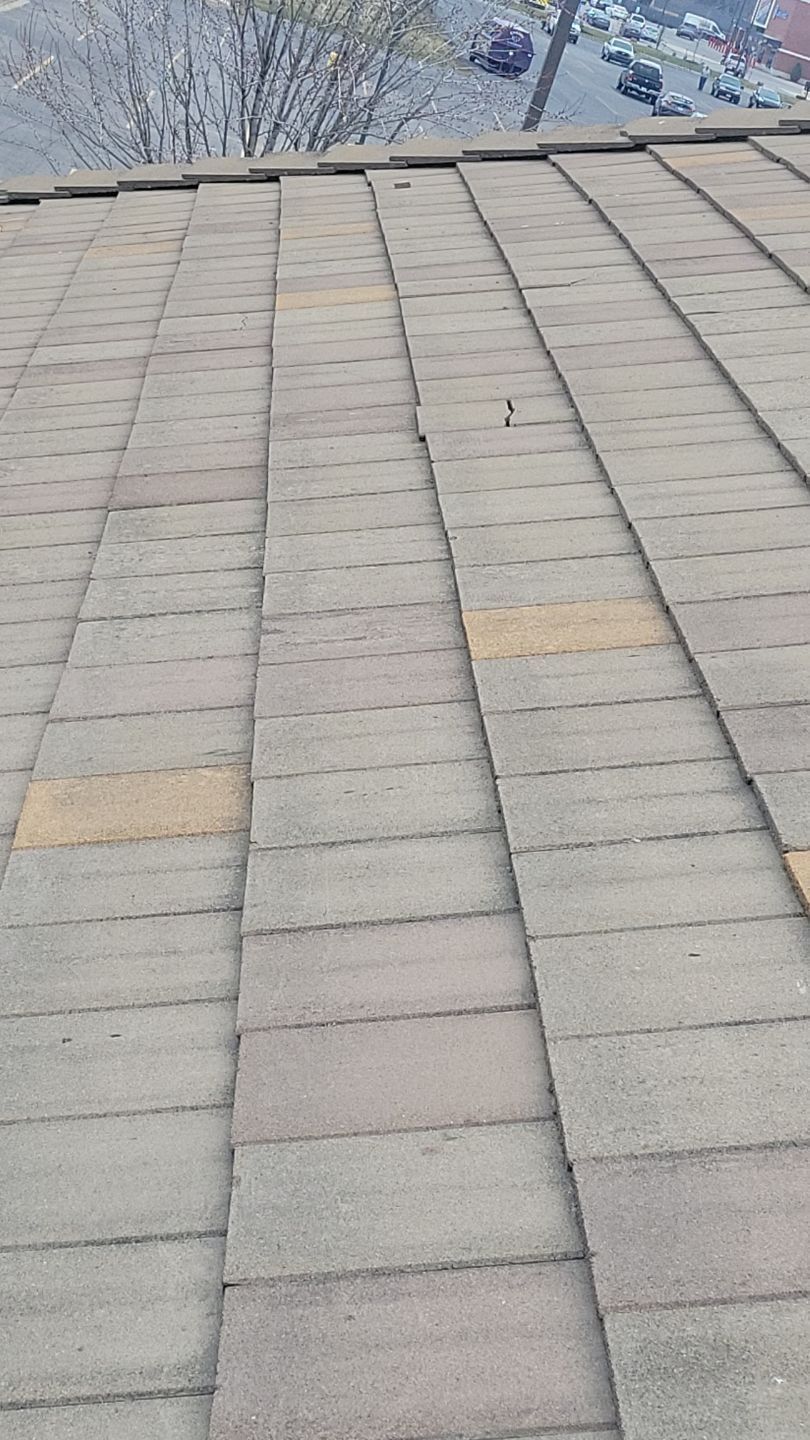 Close-up view of a brown shingled roof with some discoloration.