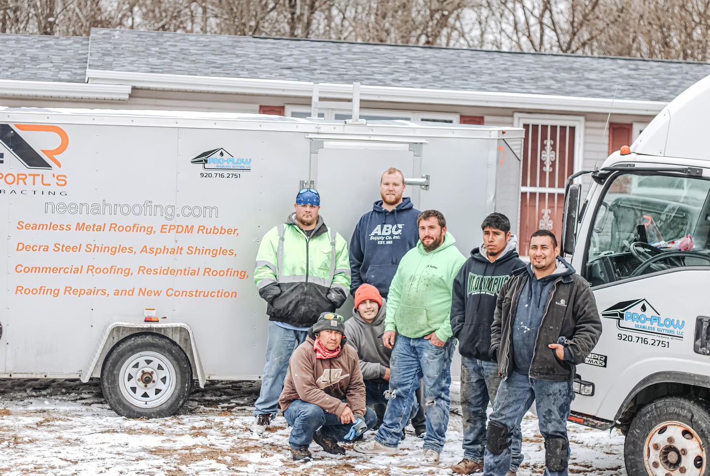 A group of men are posing for a picture in front of a truck in the snow.
