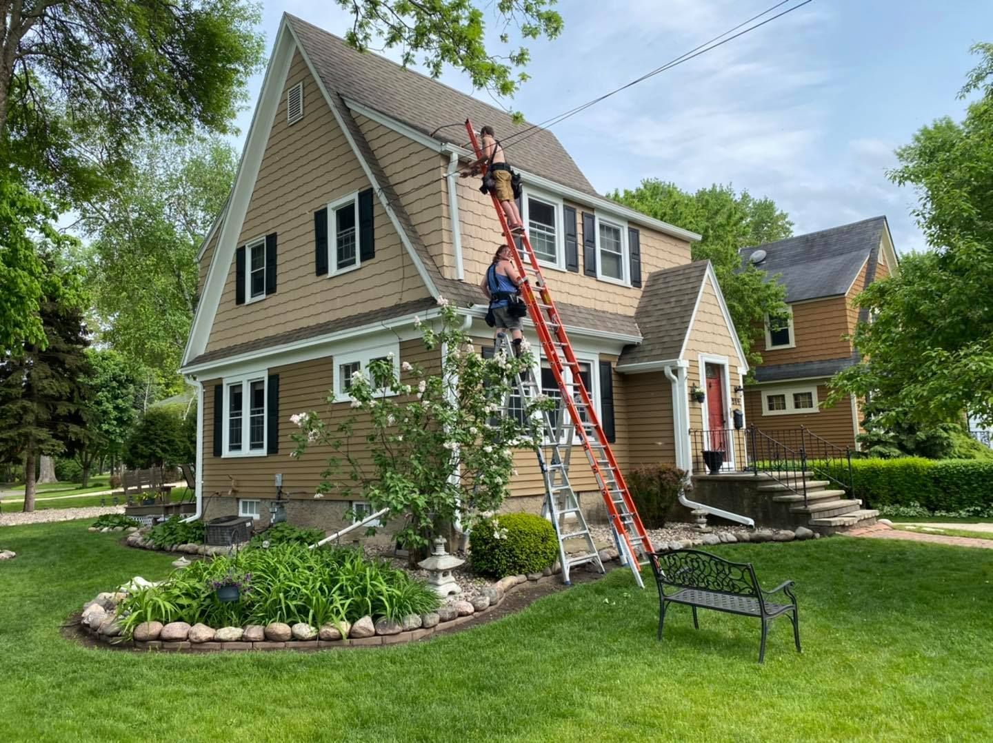 A man on a ladder is painting the side of a house.