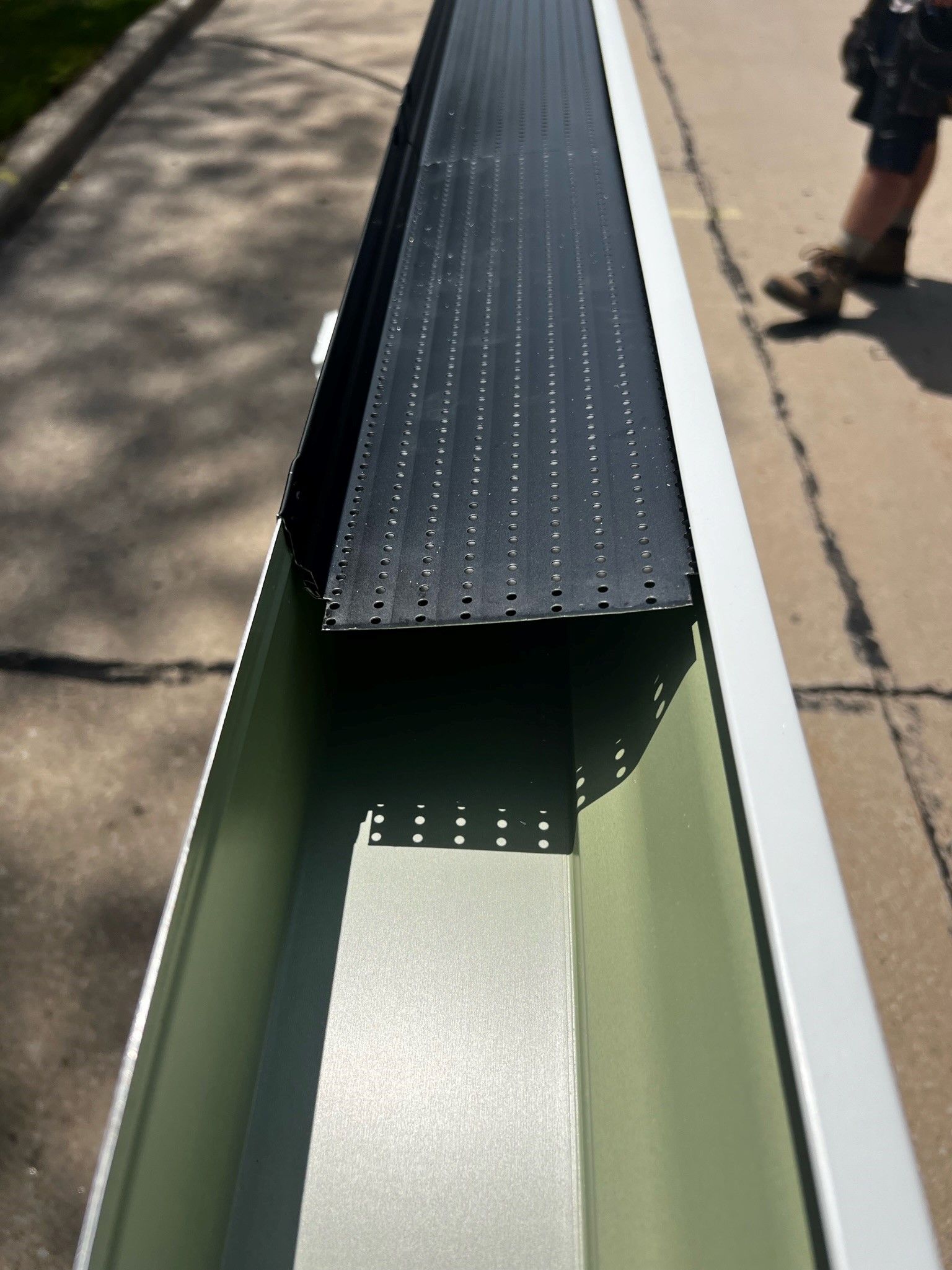 A person is standing next to a gutter on the sidewalk