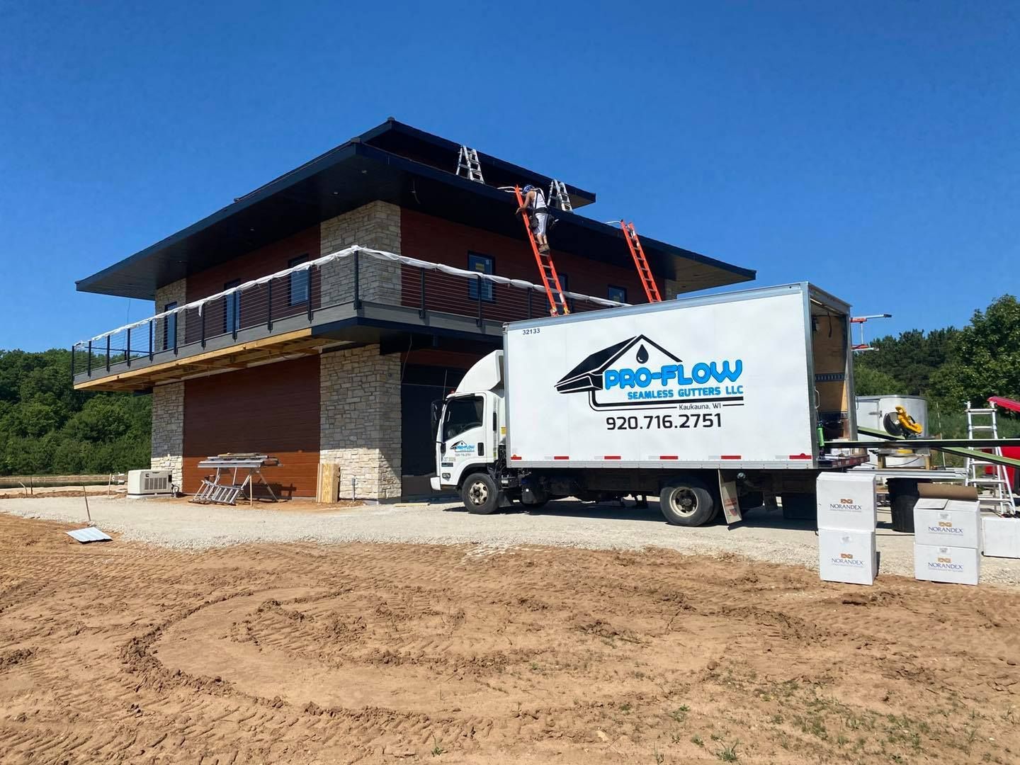 A pro-flow truck is parked in front of a house under construction.