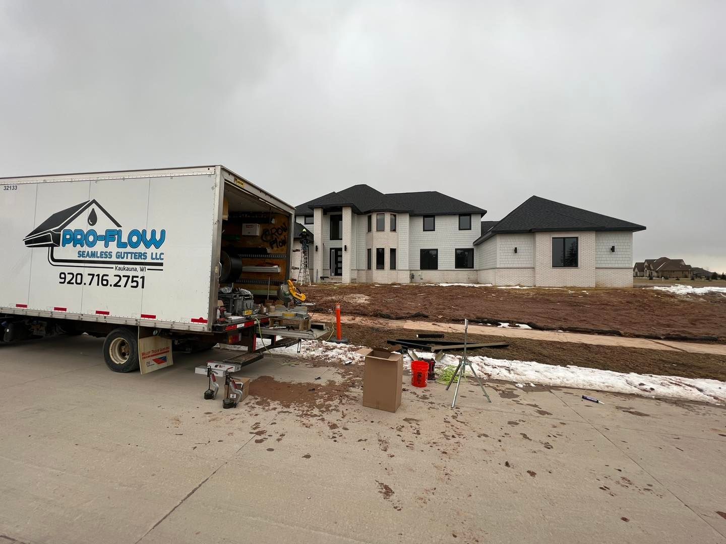 A white pro-flow truck is parked in front of a house under construction.