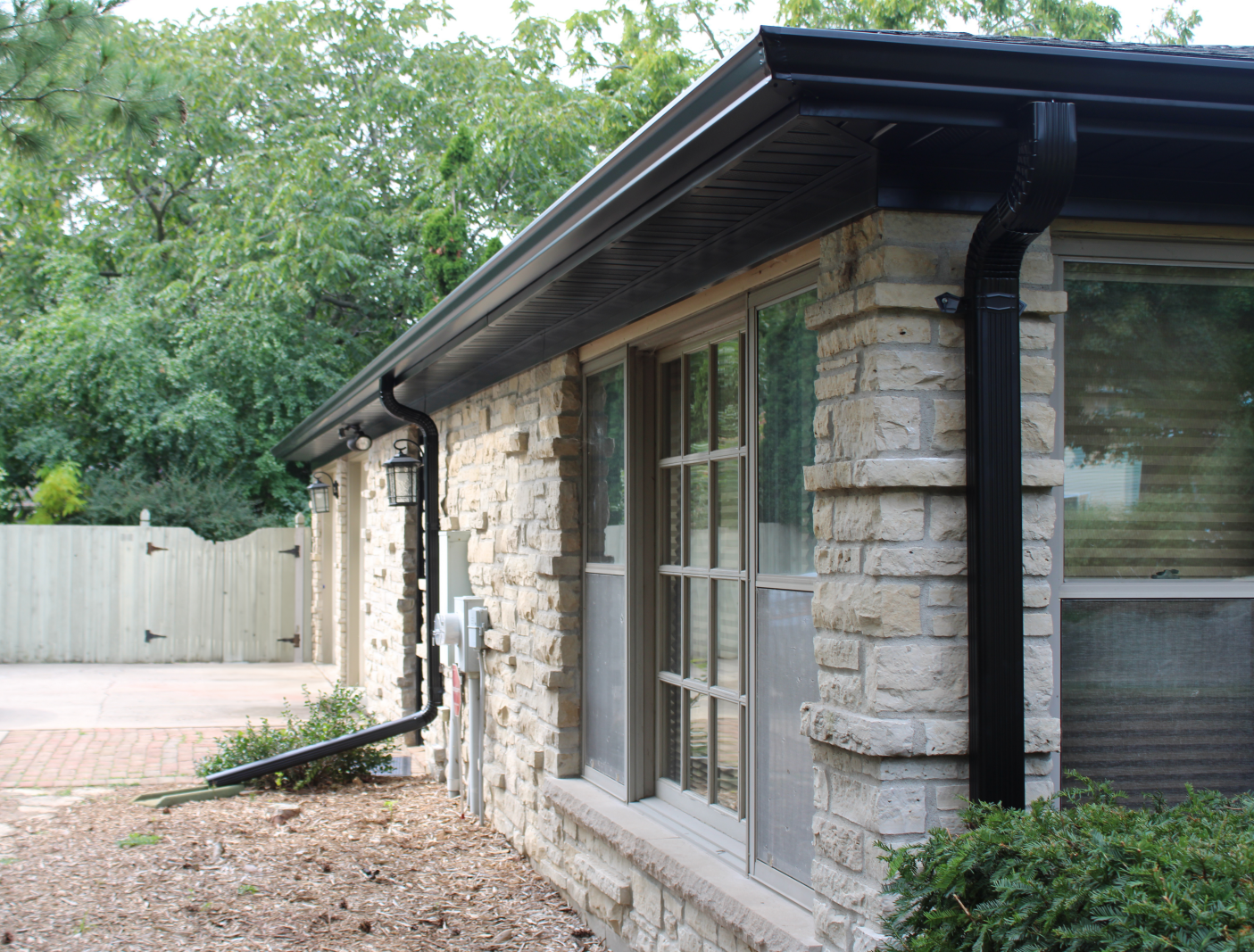 A brick house with a black gutter on the side
