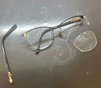 a pair of glasses with a broken lens on a table