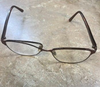 a pair of glasses with a broken frame are sitting on a table .