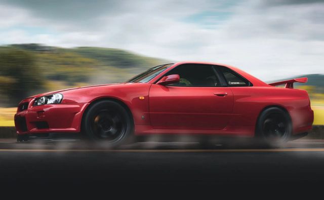 Red sports coupe speeding on a blurred road with a mountainous backdrop