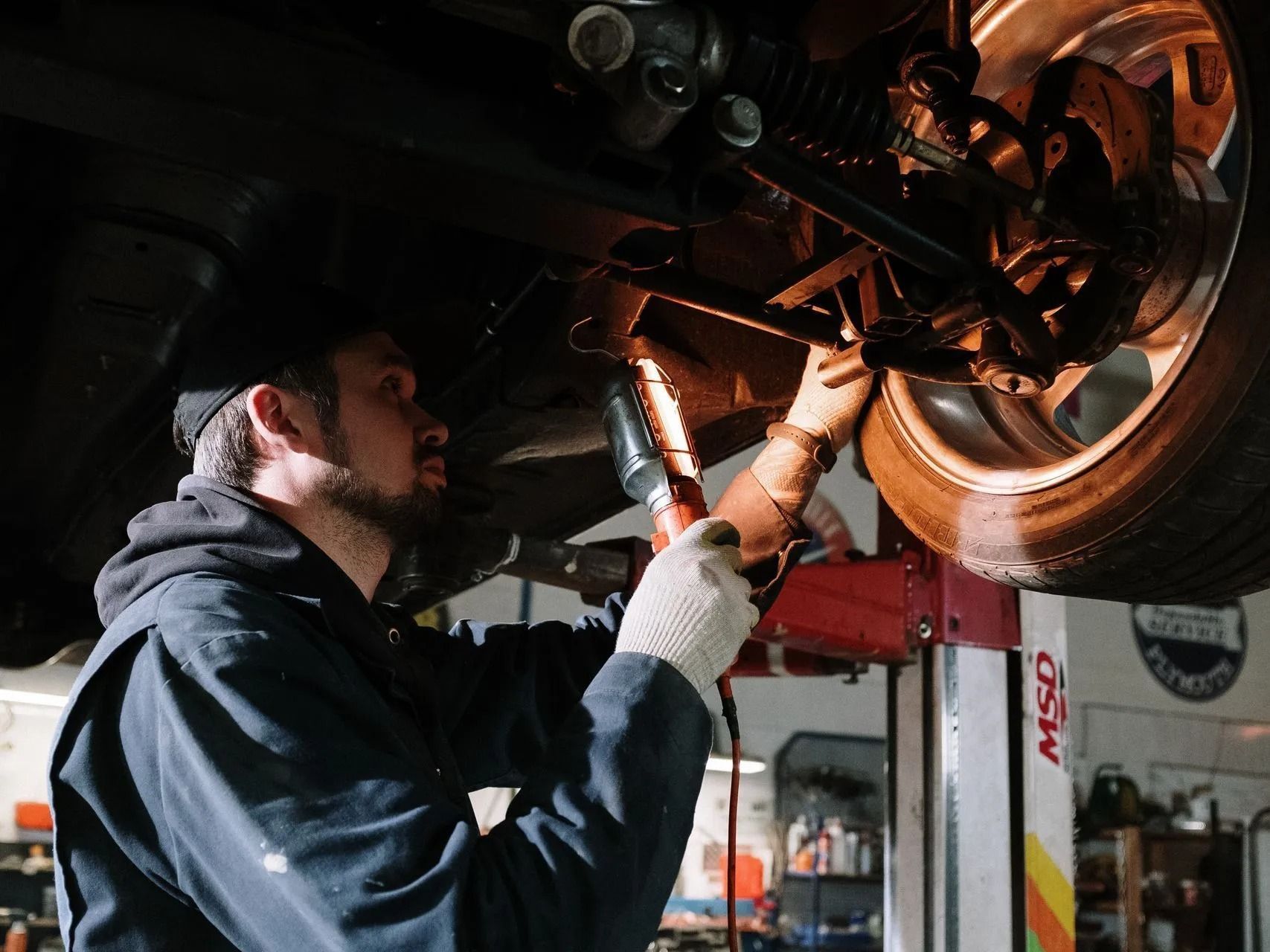 Mechanic inspecting a car’s underside on a lift in a repair shop