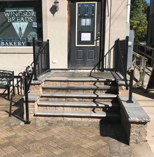Stone steps with black railings leading to a bakery entrance, with a “Windsor Breads” sign on the left.