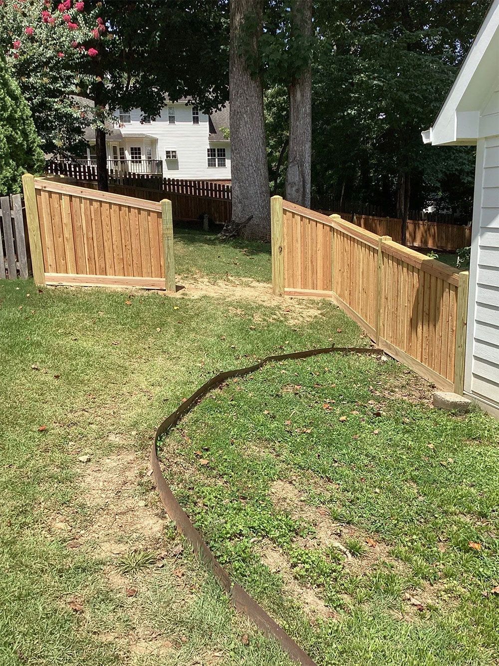 Wooden fence segments in a yard, with a pathway carved out.