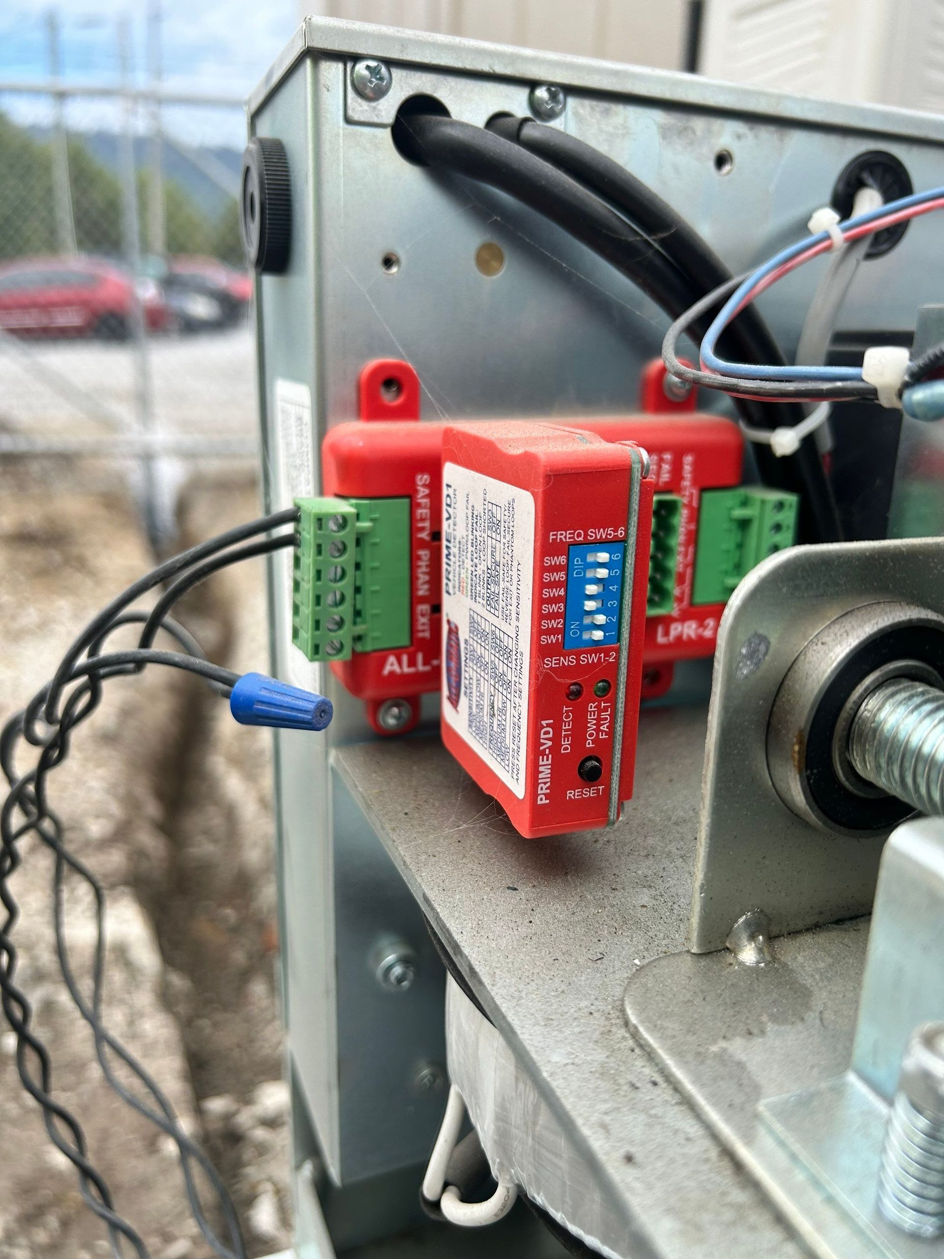 Red electronic components with green terminals, wired inside a metal enclosure.