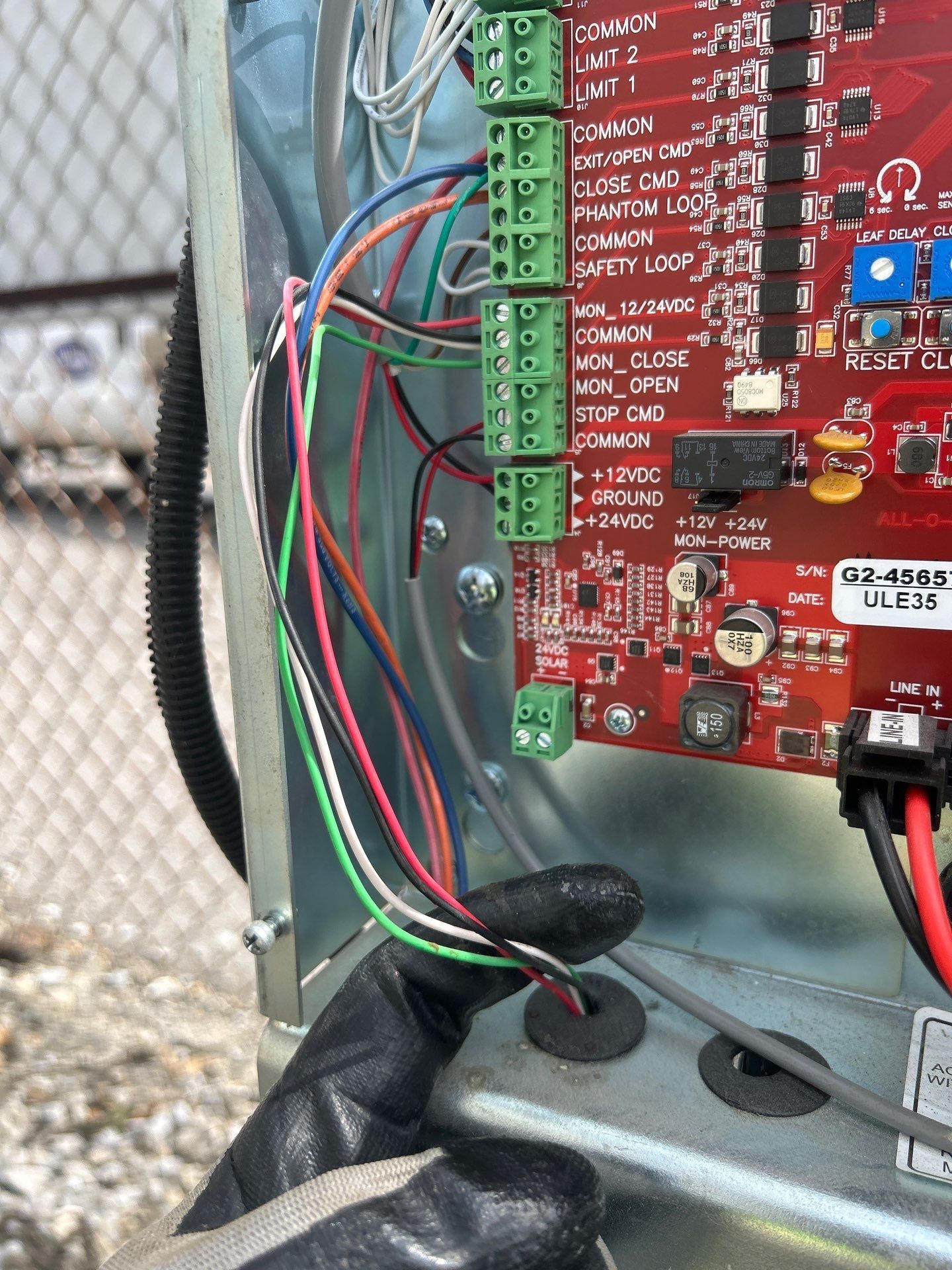 Close-up of a circuit board with colored wires connected to green terminals inside a metal box.