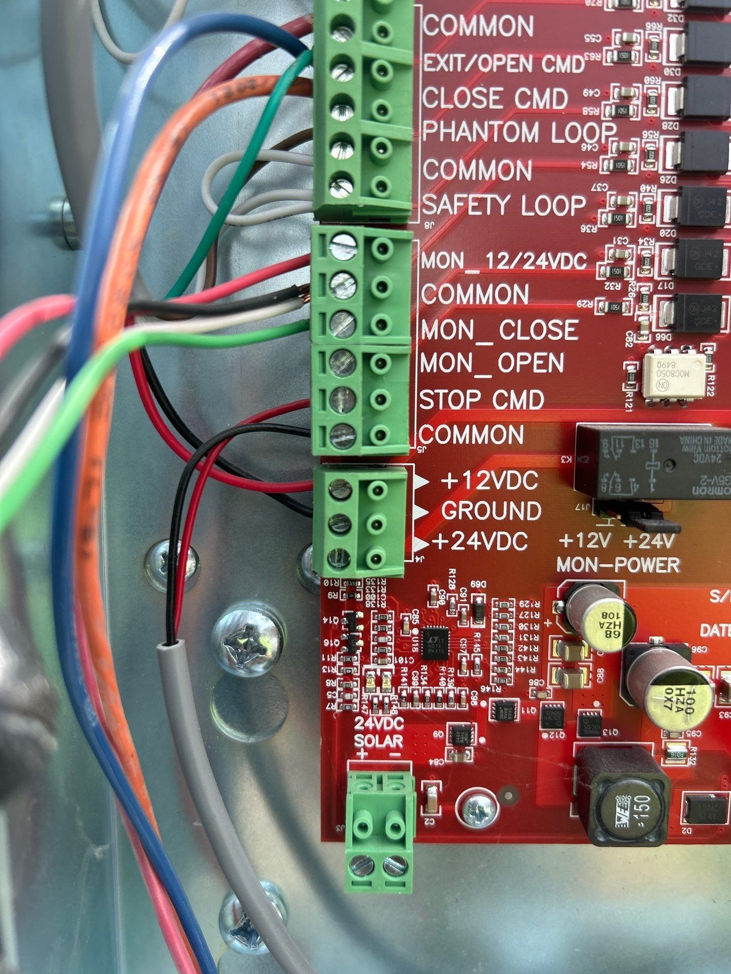Close-up of a circuit board with green terminal blocks and connected wires, labeled with control and power functions.