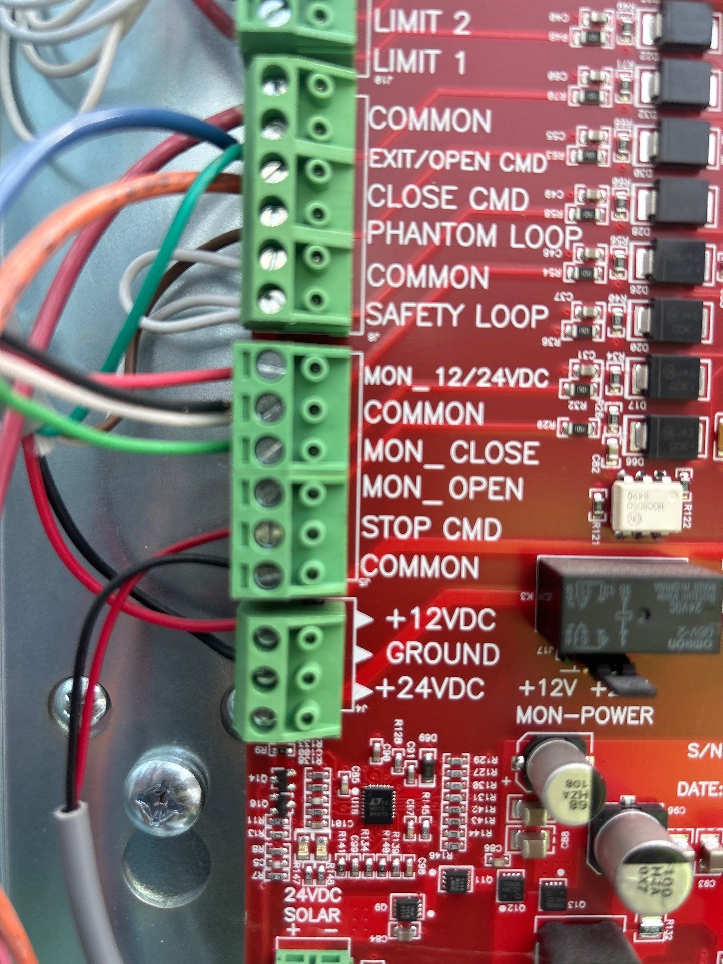 Close-up of a circuit board with various labeled terminal blocks and connected wires in different colors.