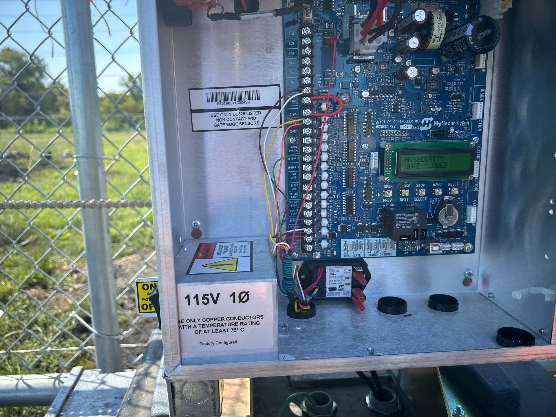 Open metal box with circuit board, wiring, and a 115V power supply.