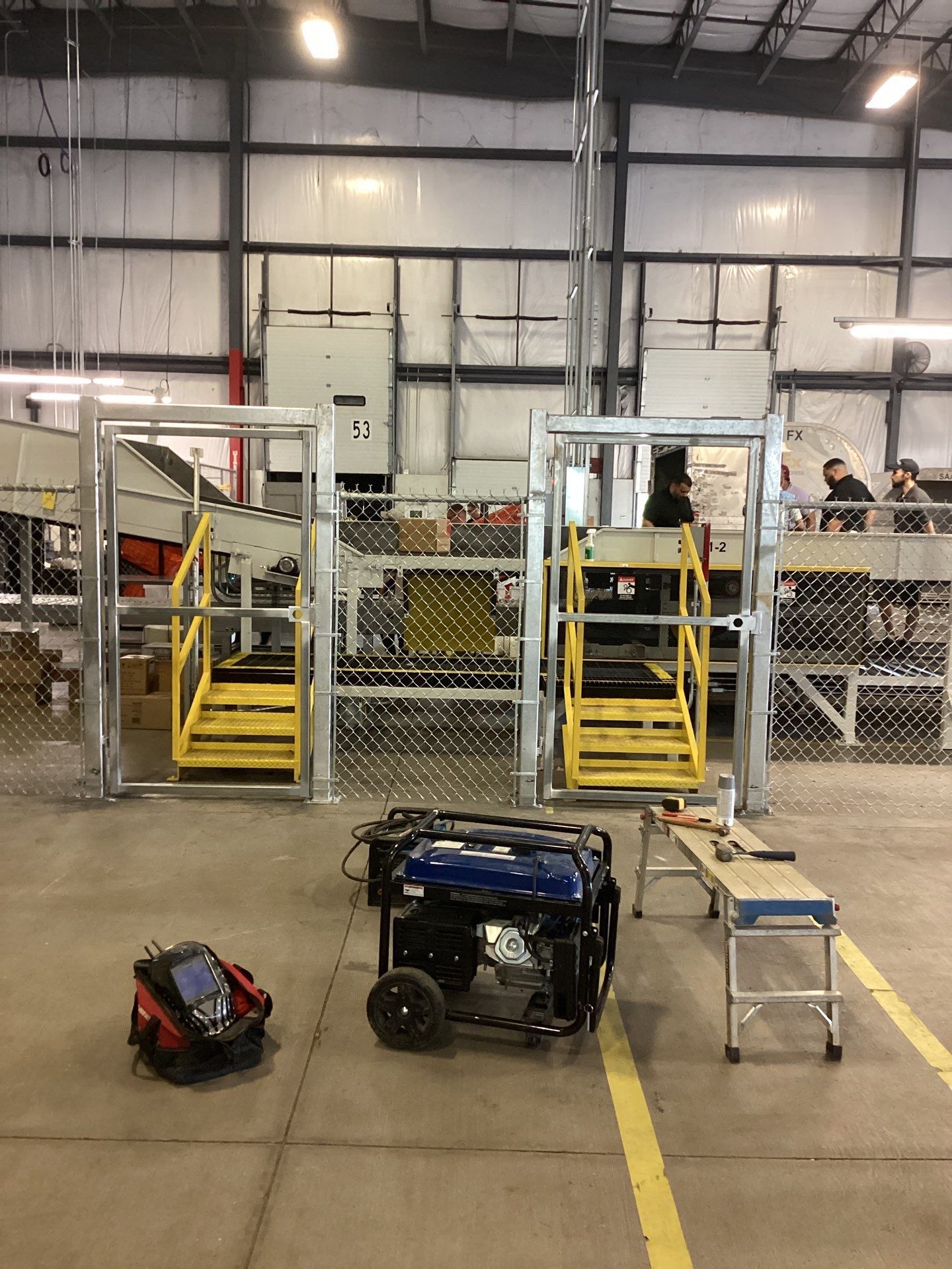 An industrial interior with two fenced platforms, a generator, and tools. Yellow stairs lead to each platform.