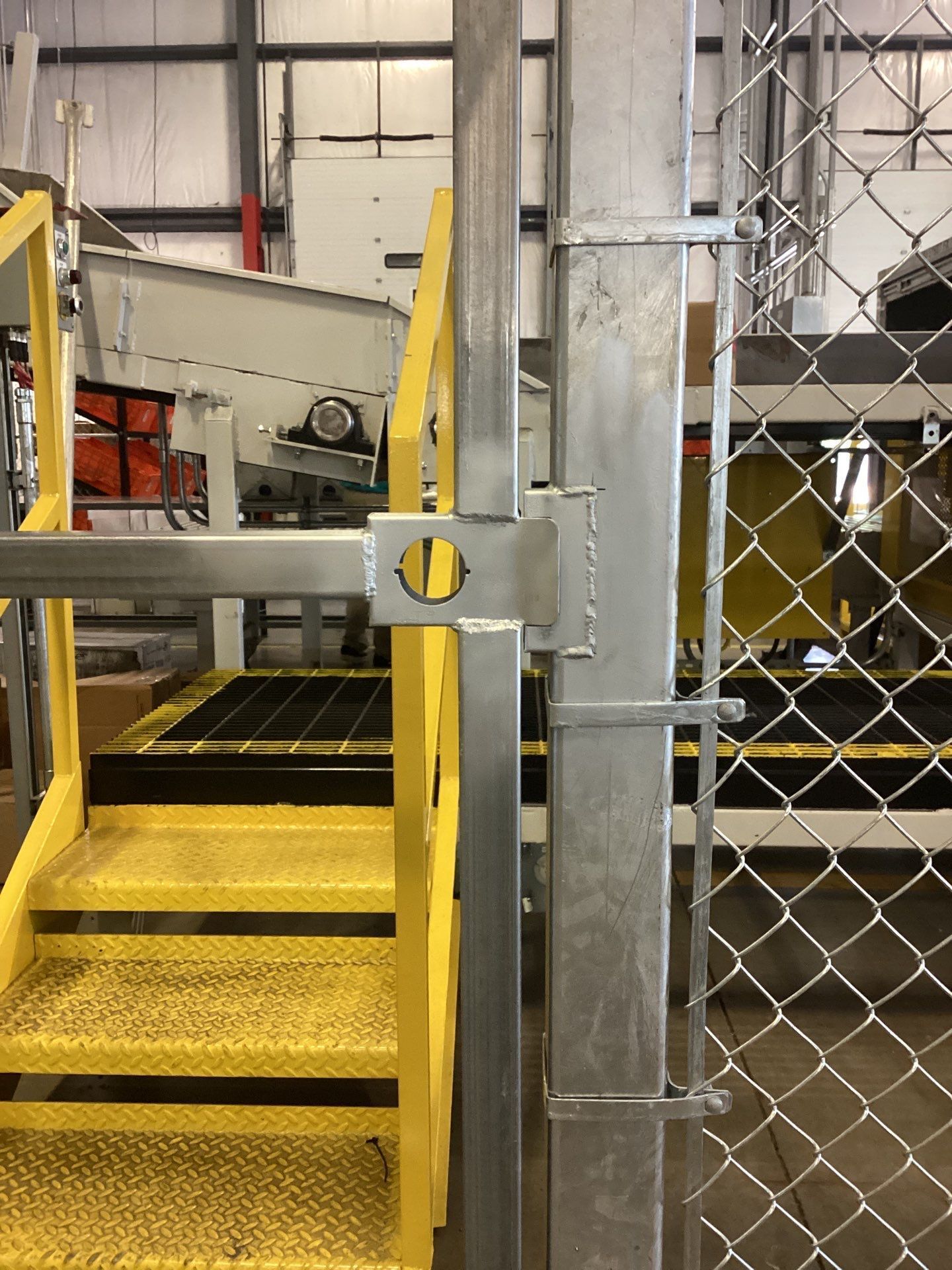 Yellow stairs and platform next to a metal fence post.