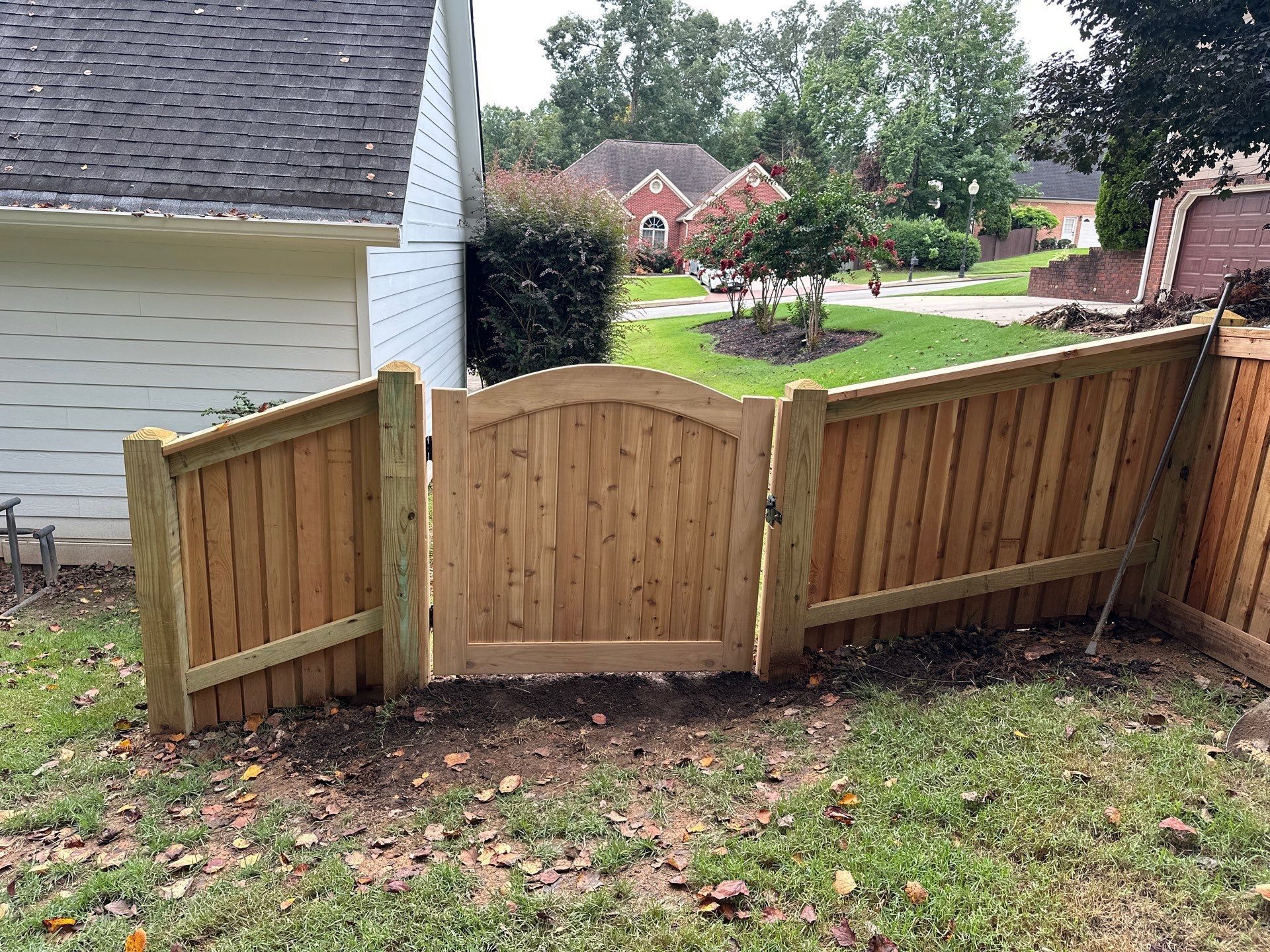 Wooden fence with arched gate in front of a house.