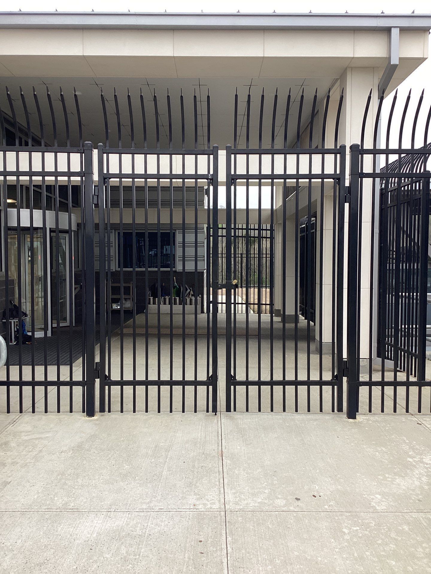 Black metal gate in front of a building with a concrete floor.