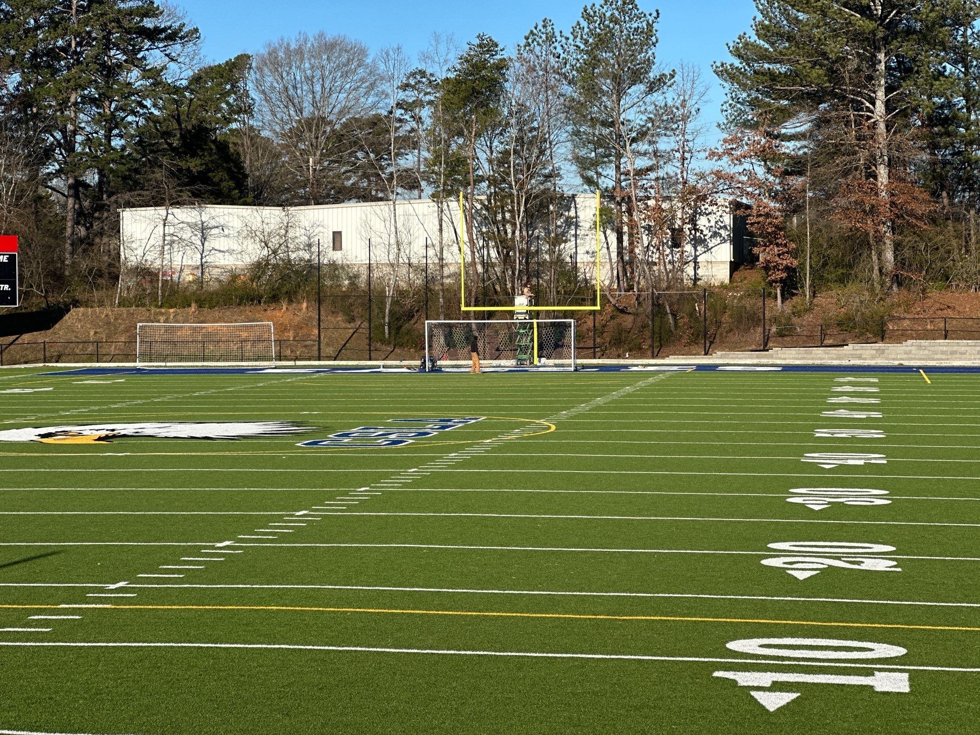 Football field with goalpost; white yard markers; clear sky.