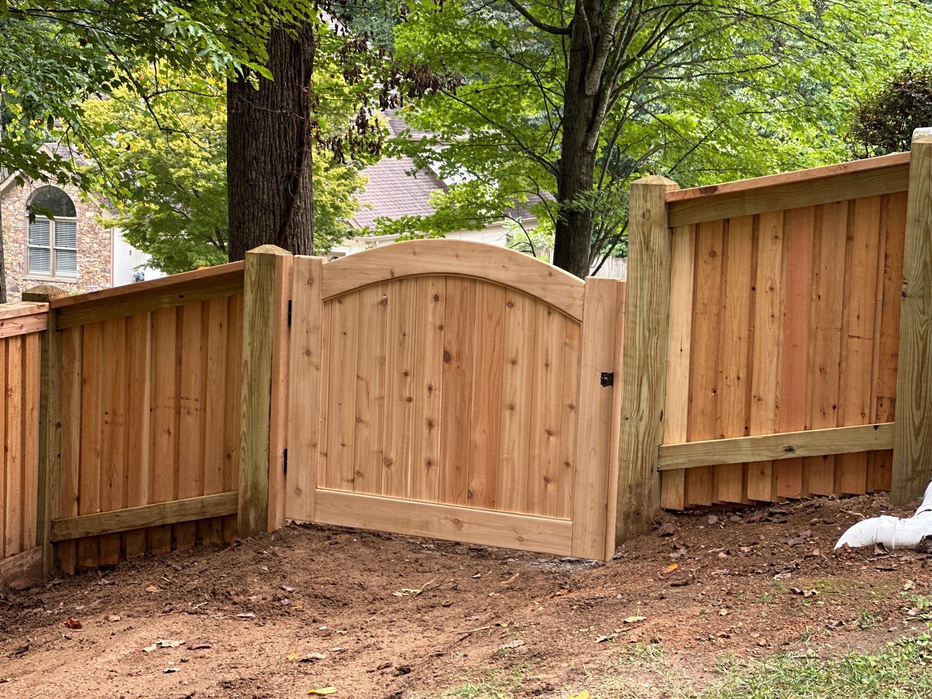 Wooden gate with arched top, integrated into a cedar fence.