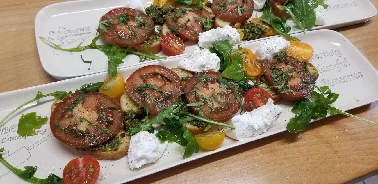 Platters of tomato and cheese salad with pesto and arugula.