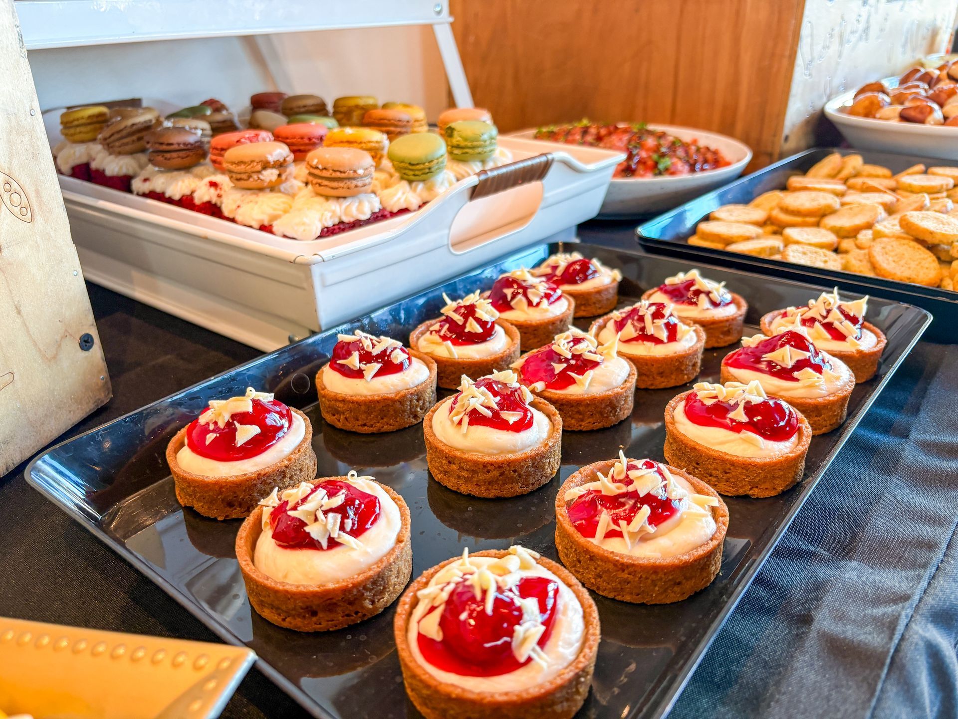 Dessert buffet: Mini cheesecakes with cherries, macarons, and other treats on a table.