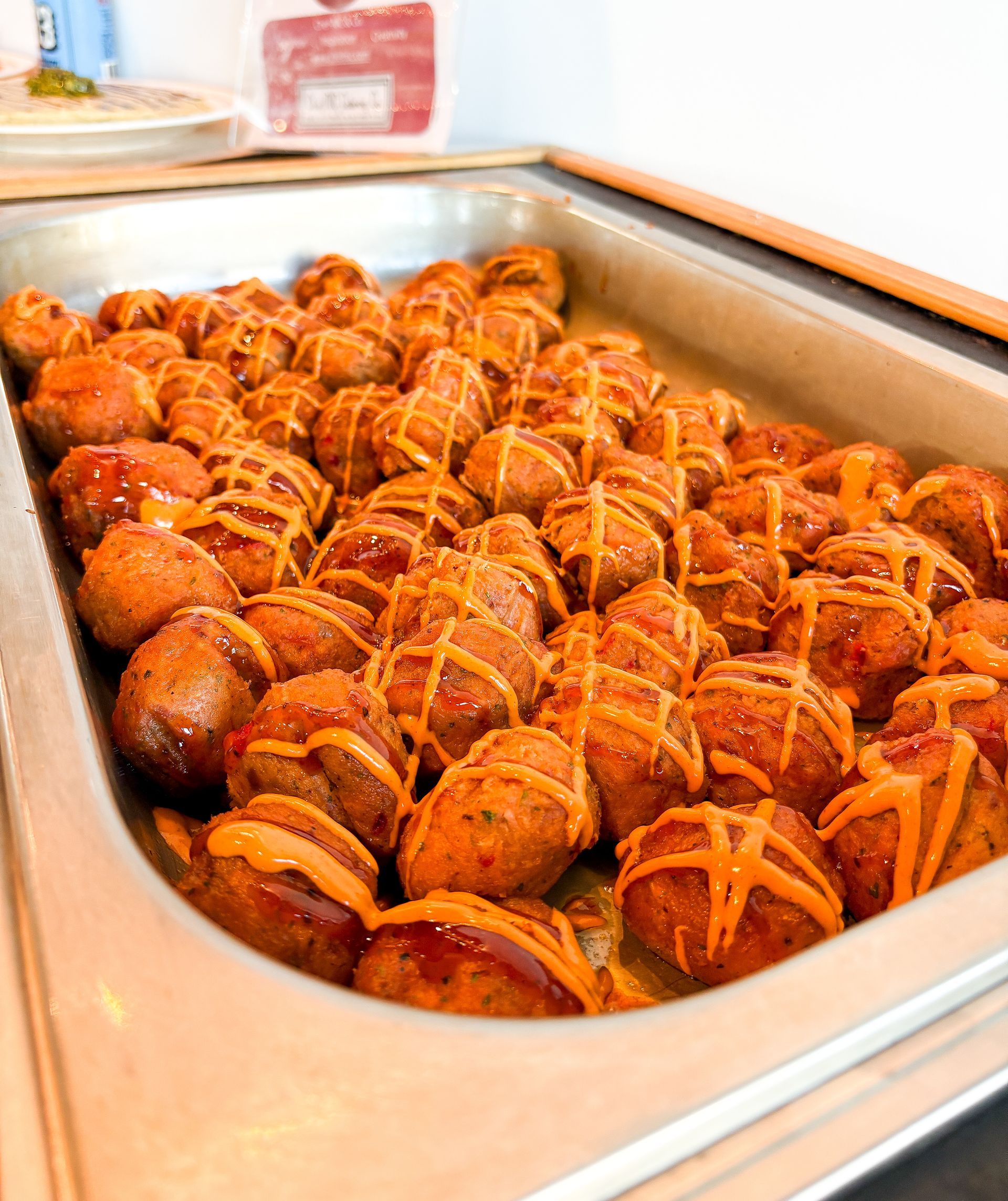 Tray of fried food balls drizzled with orange sauce.